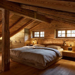 Großes Uriges Hauptschlafzimmer ohne Kamin mit brauner Wandfarbe, gebeiztem Holzboden und braunem Boden in München