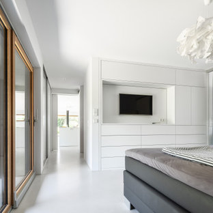 Foto de dormitorio principal, moderno, de tamaño medio, con paredes blancas, suelo de cemento, chimeneas suspendidas y suelo gris