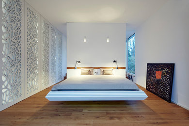 ケルンにある中くらいなコンテンポラリースタイルのおしゃれな主寝室 (白い壁、無垢フローリング、暖炉なし、茶色い床) のレイアウト