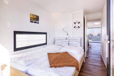 Kleines Maritimes Schlafzimmer mit weißer Wandfarbe, braunem Holzboden und braunem Boden in Berlin
