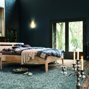 Imagen de dormitorio principal, campestre, grande, con paredes azules, suelo de madera pintada y estufa de leña