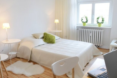 Foto de dormitorio principal actual de tamaño medio sin chimenea con paredes blancas, suelo de madera clara y con escritorio
