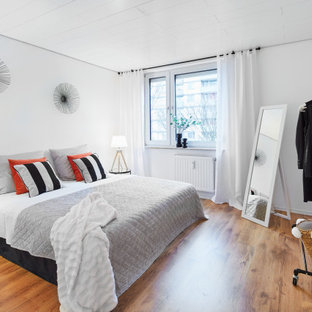 Modernes Schlafzimmer mit weißer Wandfarbe, braunem Holzboden und braunem Boden in Köln