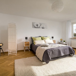 Großes Modernes Hauptschlafzimmer ohne Kamin mit weißer Wandfarbe, braunem Holzboden und braunem Boden in München