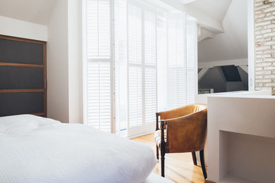 Modernes Schlafzimmer ohne Kamin mit weißer Wandfarbe und braunem Holzboden in München