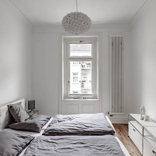 Nordisches Schlafzimmer mit weißer Wandfarbe, braunem Holzboden und braunem Boden in Hamburg