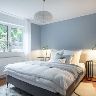 Kleines Modernes Gästezimmer mit blauer Wandfarbe, braunem Holzboden und Tapetenwänden in Stuttgart