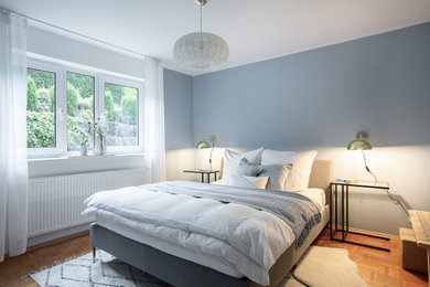 Kleines Modernes Gästezimmer mit blauer Wandfarbe, braunem Holzboden und Tapetenwänden in Stuttgart