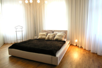Großes Modernes Schlafzimmer ohne Kamin mit braunem Holzboden in Berlin