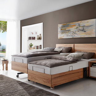 Imagen de dormitorio principal, actual, de tamaño medio, sin chimenea, con paredes marrones, suelo de madera clara, suelo blanco y marco de chimenea de madera