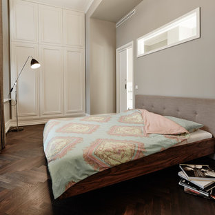 Modelo de dormitorio clásico, de tamaño medio, sin chimenea, con paredes grises, suelo de madera en tonos medios y suelo marrón