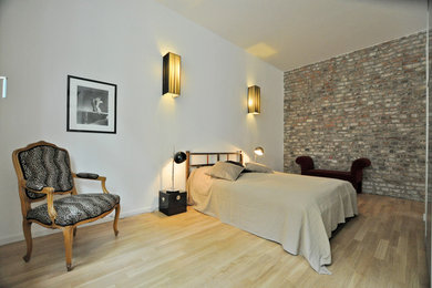 Diseño de dormitorio tipo loft tradicional renovado de tamaño medio con paredes rojas y suelo de madera clara