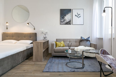 Modelo de dormitorio principal actual de tamaño medio sin chimenea con paredes blancas, suelo de madera en tonos medios y suelo marrón