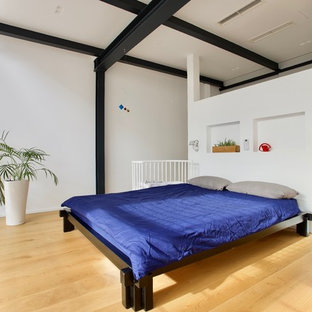 Ejemplo de dormitorio tipo loft, minimalista, grande, con paredes blancas, suelo de madera clara y suelo amarillo