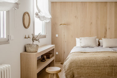 Cette image montre une chambre parentale méditerranéenne de taille moyenne avec parquet clair, un sol marron, un mur blanc et aucune cheminée.
