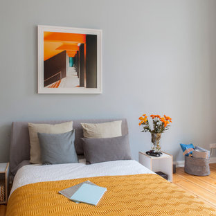 Foto de dormitorio urbano, de tamaño medio, sin chimenea, con paredes grises y suelo de madera en tonos medios