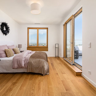 Mittelgroßes Modernes Hauptschlafzimmer ohne Kamin mit weißer Wandfarbe, braunem Holzboden und beigem Boden in München