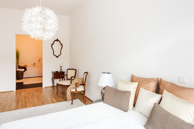 Foto de dormitorio principal clásico de tamaño medio sin chimenea con paredes blancas, suelo de madera en tonos medios y suelo marrón