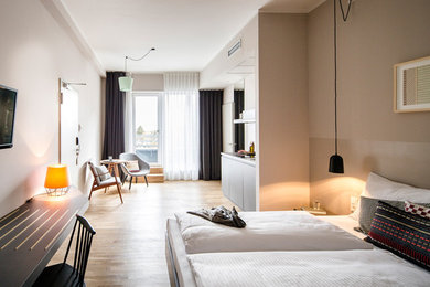 Diseño de dormitorio principal moderno de tamaño medio sin chimenea con paredes beige y suelo de madera en tonos medios