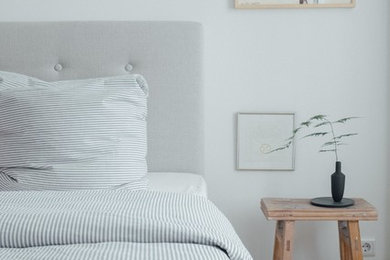 Imagen de dormitorio principal escandinavo de tamaño medio sin chimenea con paredes blancas, suelo de madera en tonos medios y suelo marrón