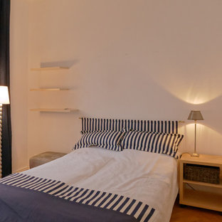 Ejemplo de dormitorio tipo loft, contemporáneo, de tamaño medio, con paredes blancas, suelo de madera en tonos medios, estufa de leña y suelo beige
