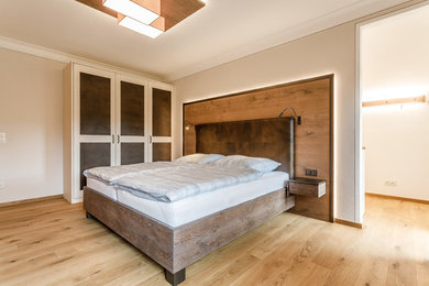 Großes Modernes Hauptschlafzimmer ohne Kamin mit beiger Wandfarbe, braunem Holzboden und braunem Boden in München