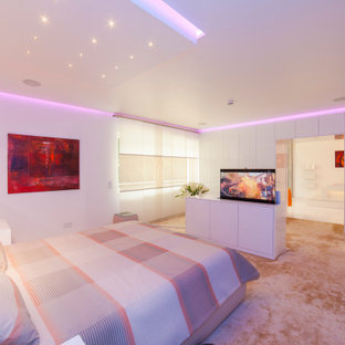 Modelo de dormitorio principal, moderno, extra grande, con paredes blancas, moqueta y suelo beige