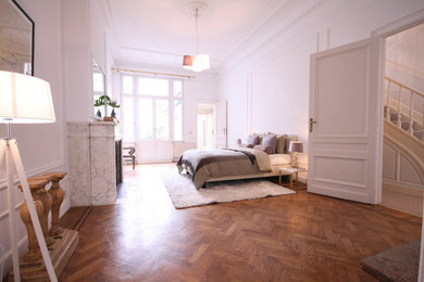 Geräumiges Schlafzimmer mit weißer Wandfarbe, braunem Holzboden und Kamin in Frankfurt am Main