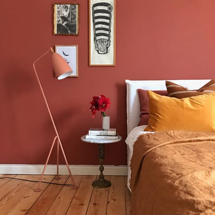 Ejemplo de dormitorio principal, ecléctico, de tamaño medio, con paredes rojas, suelo de madera clara y suelo marrón