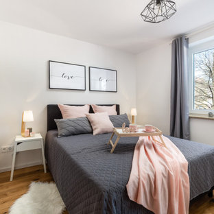 Mittelgroßes Skandinavisches Schlafzimmer mit weißer Wandfarbe, braunem Holzboden und braunem Boden in München
