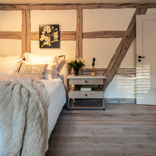 Modelo de dormitorio principal, de estilo de casa de campo, grande, con paredes beige, suelo de madera pintada y suelo gris