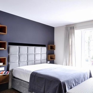Foto de dormitorio principal, tradicional, grande, sin chimenea, con paredes púrpuras, suelo de madera oscura, marco de chimenea de hormigón y suelo marrón