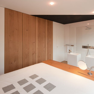 Imagen de dormitorio principal, contemporáneo, de tamaño medio, con paredes blancas, suelo de madera clara y suelo marrón