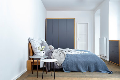 ベルリンにある中くらいな北欧スタイルのおしゃれな主寝室 (白い壁、塗装フローリング、暖炉なし、茶色い床) のインテリア