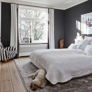 Großes Modernes Hauptschlafzimmer mit schwarzer Wandfarbe, Kamin, Kaminumrandung aus Holz, braunem Boden und braunem Holzboden in Hamburg