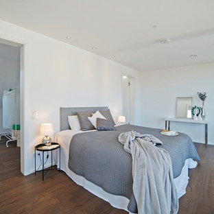 Mittelgroßes Modernes Hauptschlafzimmer ohne Kamin mit weißer Wandfarbe, braunem Holzboden und braunem Boden in München