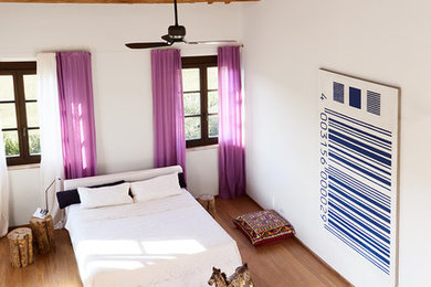 Ispirazione per una camera da letto stile loft mediterranea con pareti bianche e parquet scuro