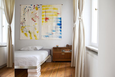 Mittelgroßes Stilmix Schlafzimmer ohne Kamin mit weißer Wandfarbe und braunem Holzboden in Berlin