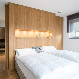 Mittelgroßes Nordisches Hauptschlafzimmer ohne Kamin mit weißer Wandfarbe, braunem Holzboden und braunem Boden in Stuttgart