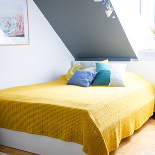 Ejemplo de habitación de invitados moderna, sin chimenea, con suelo de madera clara y paredes grises