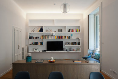 Diseño de biblioteca en casa cerrada contemporánea de tamaño medio con paredes blancas, suelo de madera clara y pared multimedia