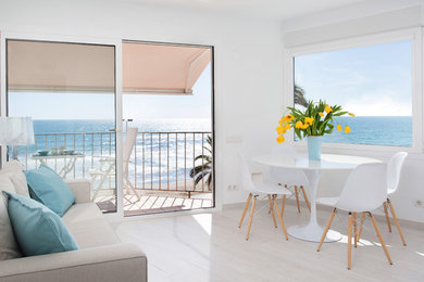 Diseño de sala de estar abierta costera de tamaño medio sin chimenea y televisor con paredes blancas y suelo de madera clara