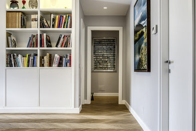 Immagine di un soggiorno contemporaneo di medie dimensioni con libreria, pareti grigie e pavimento in legno massello medio