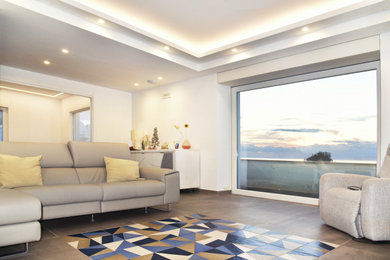 Ispirazione per un grande soggiorno mediterraneo aperto con pareti bianche, pavimento in gres porcellanato e pavimento grigio