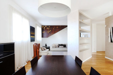 Immagine di un soggiorno design di medie dimensioni e aperto con libreria, pareti beige, pavimento in legno massello medio e TV a parete