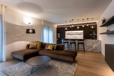 Ejemplo de sala de estar abierta contemporánea extra grande con paredes blancas, suelo de madera clara y televisor colgado en la pared