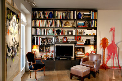 Esempio di un soggiorno minimal di medie dimensioni e aperto con libreria, pareti beige, pavimento in legno massello medio e TV a parete