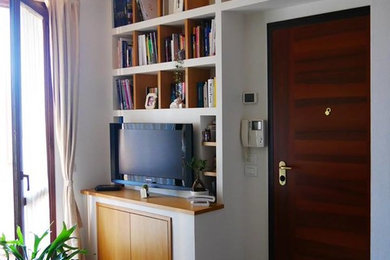 Ejemplo de biblioteca en casa abierta minimalista pequeña con paredes verdes, suelo de baldosas de porcelana, televisor colgado en la pared y suelo beige