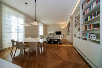 Immagine di un soggiorno moderno con libreria, pareti grigie e pavimento in legno massello medio