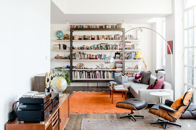 Идея дизайна: гостиная комната среднего размера в стиле фьюжн с с книжными шкафами и полками, белыми стенами, коричневым полом и темным паркетным полом
